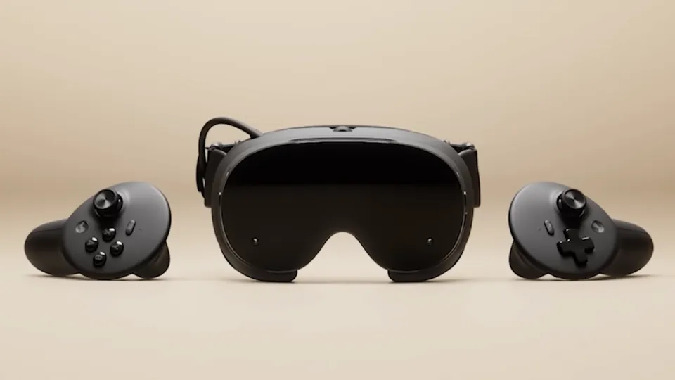 The black Steam Frame headset between its two controllers on a beige background