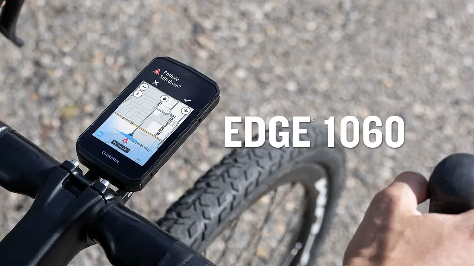 A Garmin Edge 1060 on a gravel bike handlebar shows a pothole alert asking Still there, above a street map