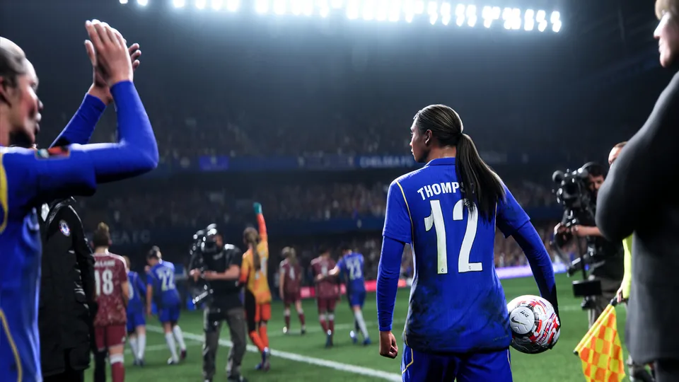 A player in a blue No. 12 shirt walks out holding a ball as teammates applaud, in EA Sports FC 27