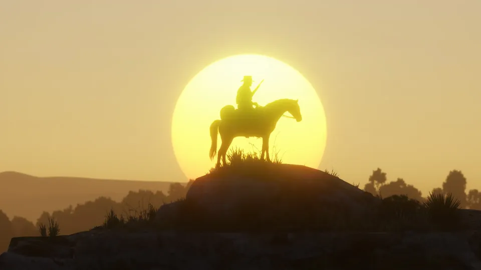 A rider silhouetted against a huge setting sun on a hilltop in Red Dead Redemption 2
