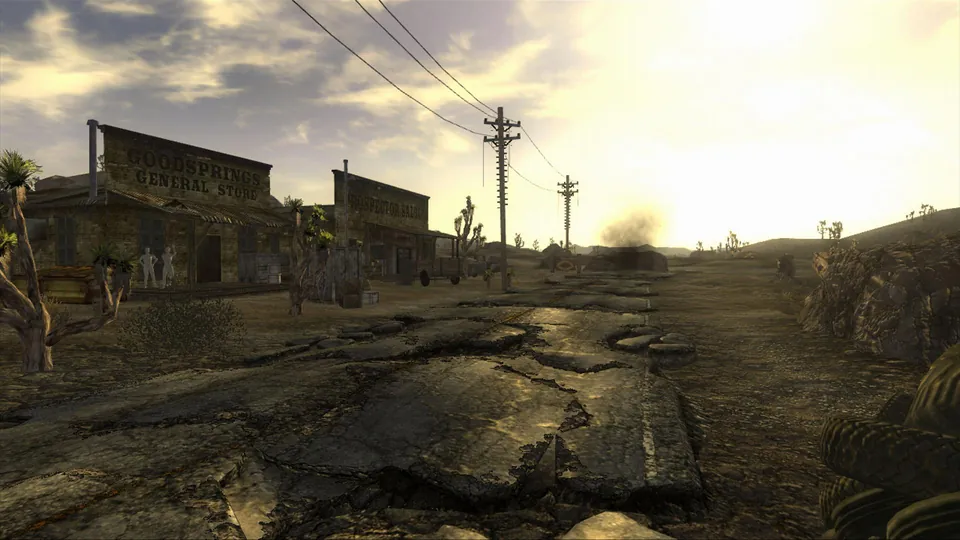 A desert road runs past weathered wooden buildings and power lines under a cloudy sky in Fallout: New Vegas