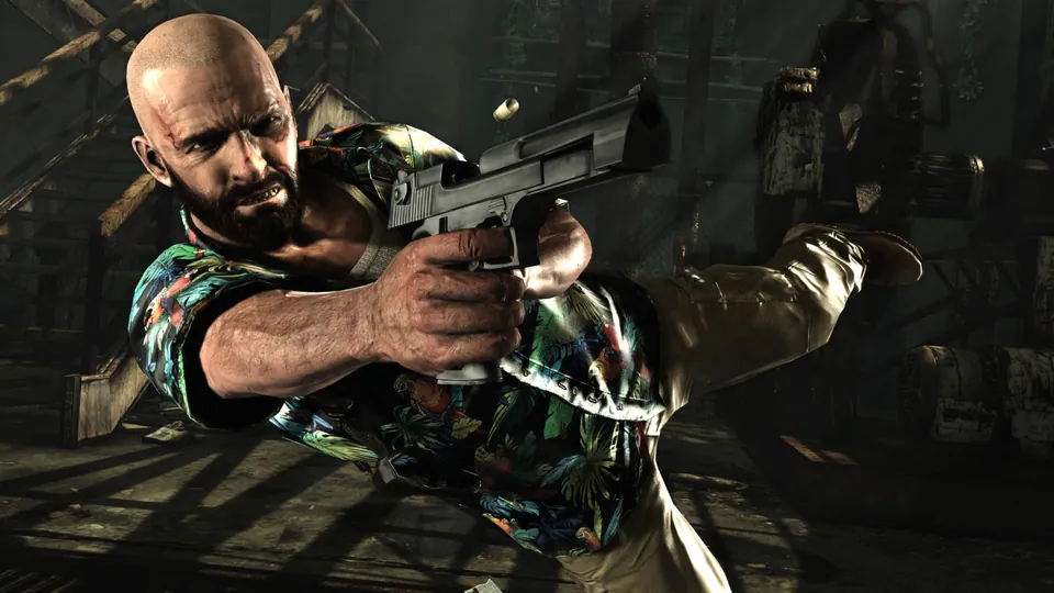 A bald Max Payne in a floral shirt dives sideways firing a pistol in Max Payne 3
