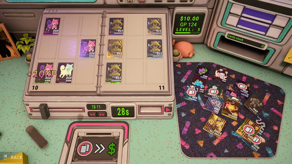 A card binder, a pile of opened booster cards and a cash counter on a desk in Rip It! Card Collector