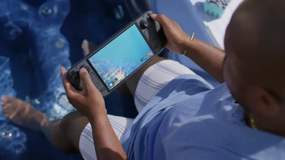 A person in a blue shirt plays a game on a Steam Deck while sitting on a couch