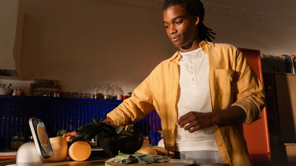 A person cooking in a kitchen looks at Apple HomeView on the counter