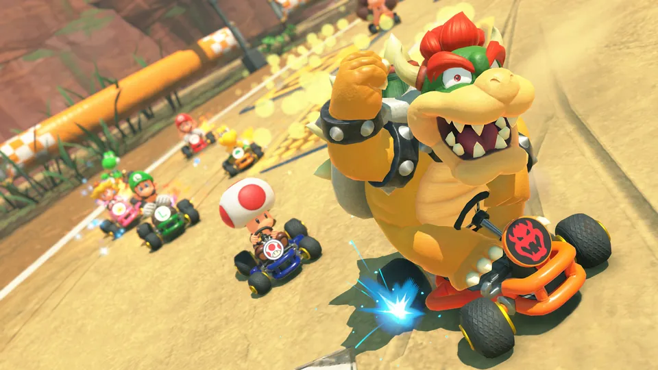 Bowser raises a fist while racing ahead of Toad and a pack of karts on the sandy Choco Island course in Mario Kart World