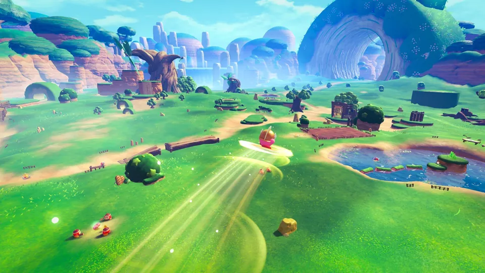 Kirby speeds across a wide green valley with hills, ponds and rock arches in Kirby and the World Beyond.