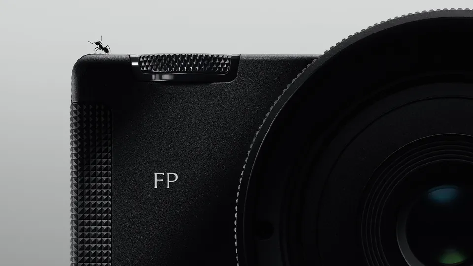 Close-up of the black Sigma FP2 body with a knurled dial and FP logo next to a large lens, with a tiny ant standing on the top plate