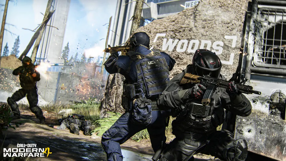 Operators trade fire in front of a wall spray-painted with the word Woods inside a training facility