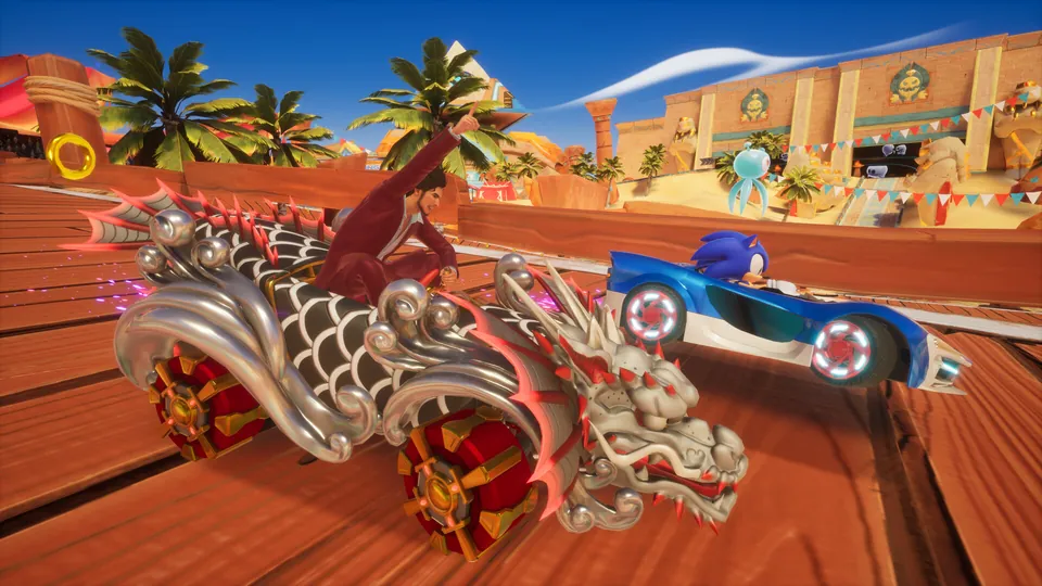 Sonic races a blue car past a dragon-shaped vehicle on a desert track in Sonic Racing: CrossWorlds.