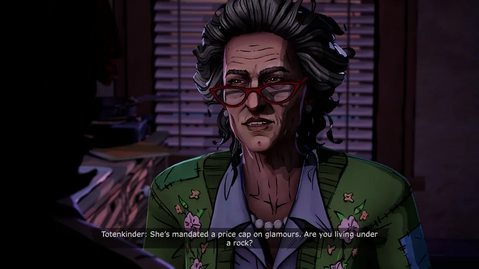 Frau Totenkinder, a gray-haired woman in red glasses and a floral cardigan, talks in an office with closed blinds