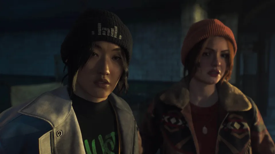 Two crew members in beanies and jackets look ahead in a dim room in Until Dawn 2