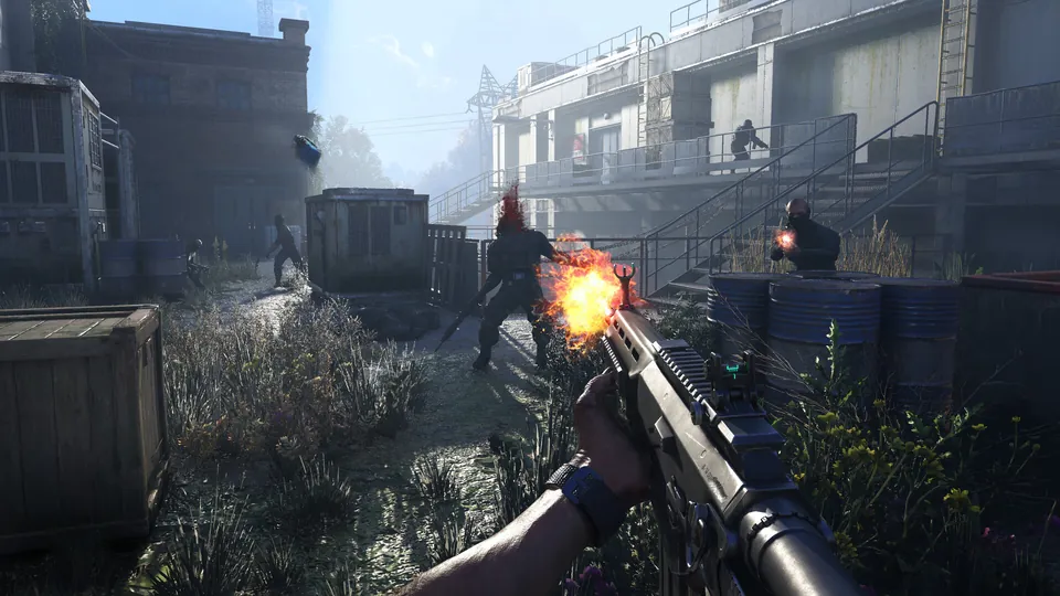 First-person view of an assault rifle firing at an infected in a sunlit industrial yard with shipping containers.
