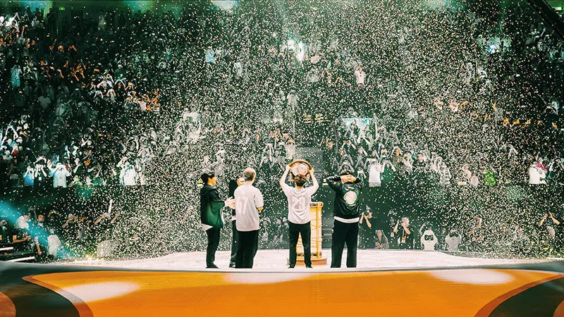 Team Spirit players lifting the Aegis of Champions on stage under falling confetti