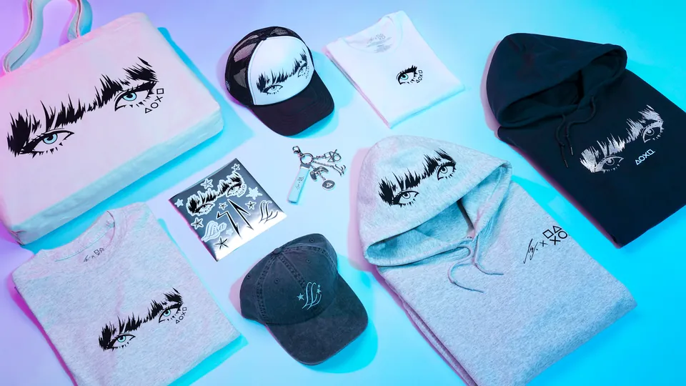 LISA x PlayStation merch laid out, with hoodies, caps, T-shirts, a keychain, stickers and a canvas tote bag printed with LISA's eyes