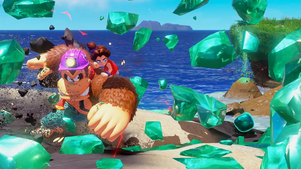 Donkey Kong in a mining helmet smashes through the ground with Pauline on board as green emeralds fly on a beach in Donkey Kong Bananza