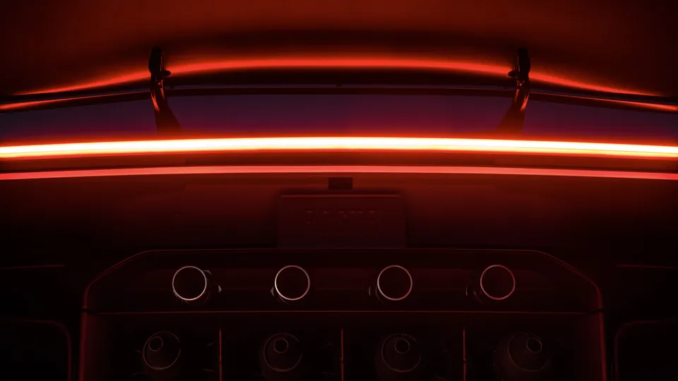 The rear of the new Tesla Roadster with its full-width red taillight and four thruster nozzles glowing