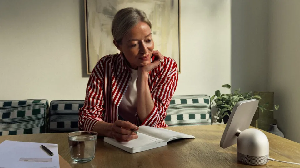 A person writing at a dining table next to a white HomeView