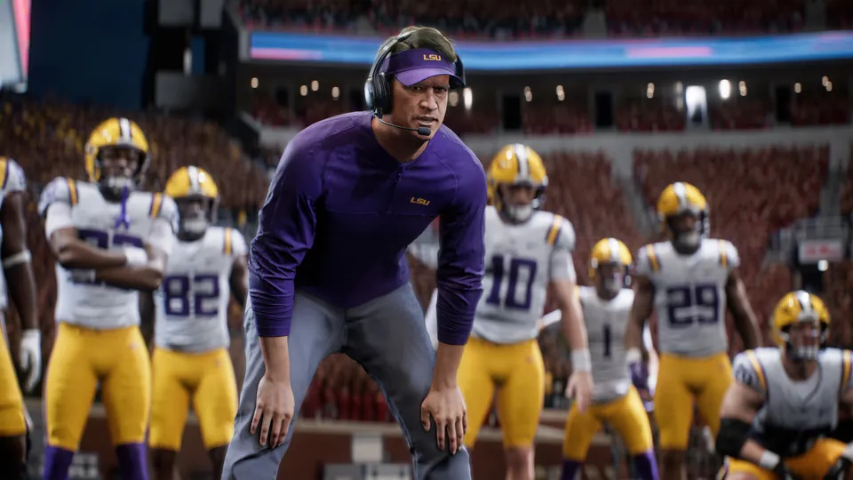 An LSU coach in a headset crouches on the sideline in front of his players in College Football 27