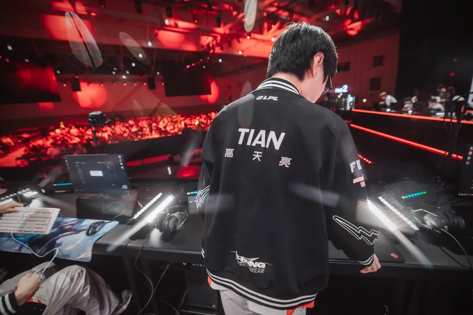Tian of Top Esports walks to the desk on stage at MSI 2026 in Daejeon, with the crowd in red light behind