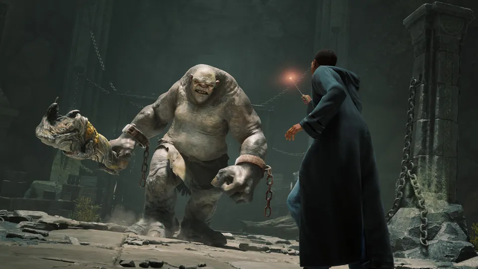 A student points a wand at a chained troll in a dark stone dungeon