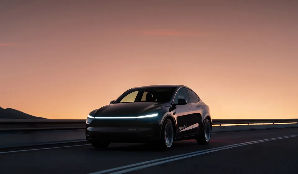 A black Tesla Model Y with Robotaxi lettering and its light bar on, driving at dusk