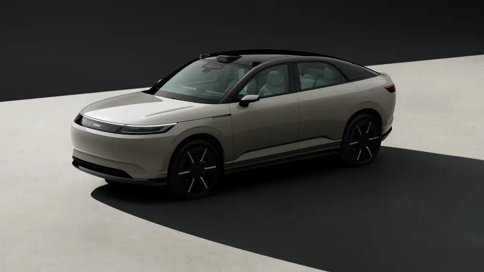 The Afeela Prototype 2026, a beige crossover with black wheels, on a black and white floor