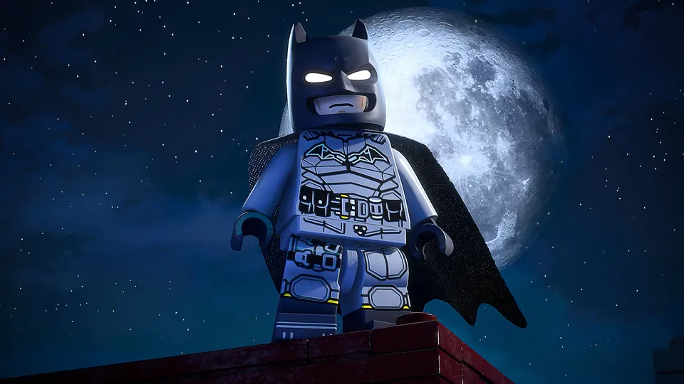 A LEGO Batman minifigure stands on a rooftop ledge in front of a full moon in LEGO Batman: Legacy of the Dark Knight