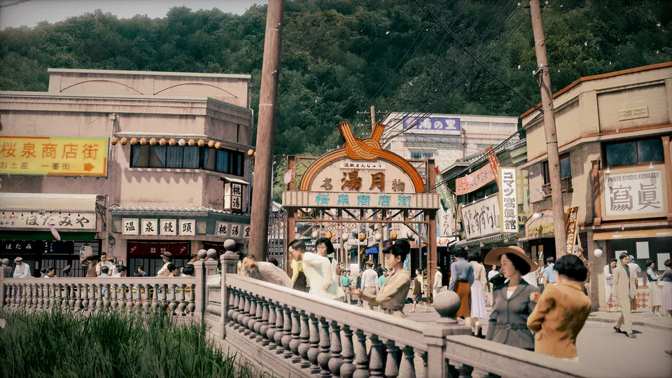 Visitors cross a stone bridge below a hot spring arch in a busy seaside resort town