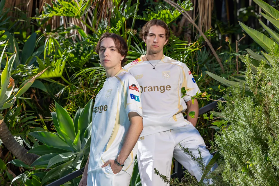 Two Karmine Corp players in white jerseys pose among palms at a Worlds 2026 Play-In photo shoot in Los Angeles