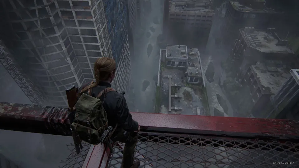 A survivor with a backpack looking down at a ruined, overgrown city from a skyscraper in The Last of Us Part II Remastered