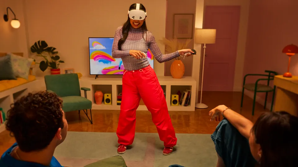 A person wearing a Meta Quest headset plays in a living room while two friends watch from the floor