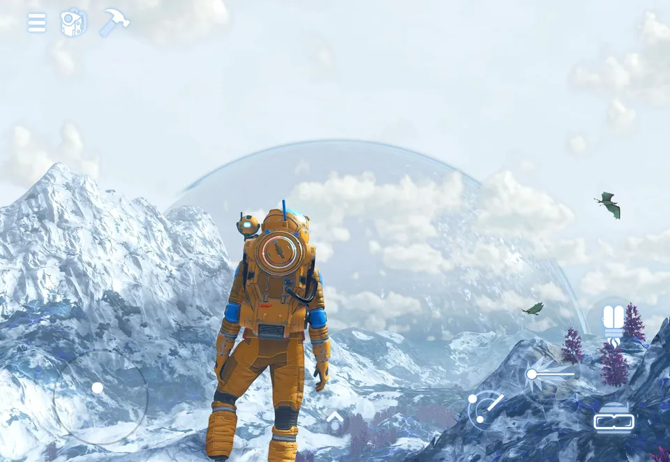 An explorer in an orange suit stands on a snowy mountain below a huge pale planet in No Man's Sky on iPad