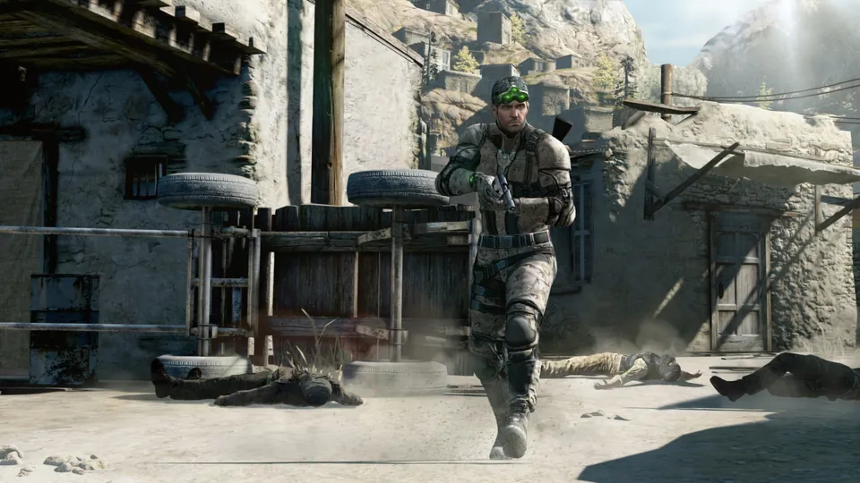 Sam Fisher walks through a sunlit desert village past fallen guards in Splinter Cell: Blacklist