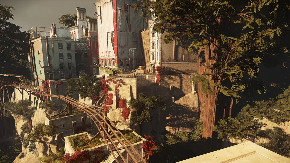 Sunlit stone buildings and an elevated rail line cling to a green cliffside in the coastal city of Karnaca in Dishonored 2