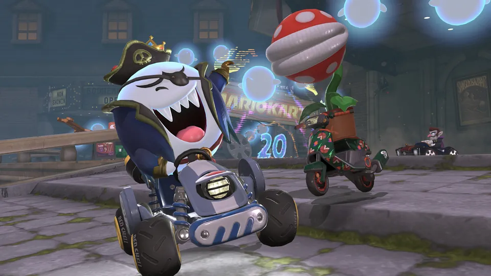 King Boo in a pirate hat and eye patch drives a kart ahead of a Piranha Plant rider on a city street in Mario Kart World