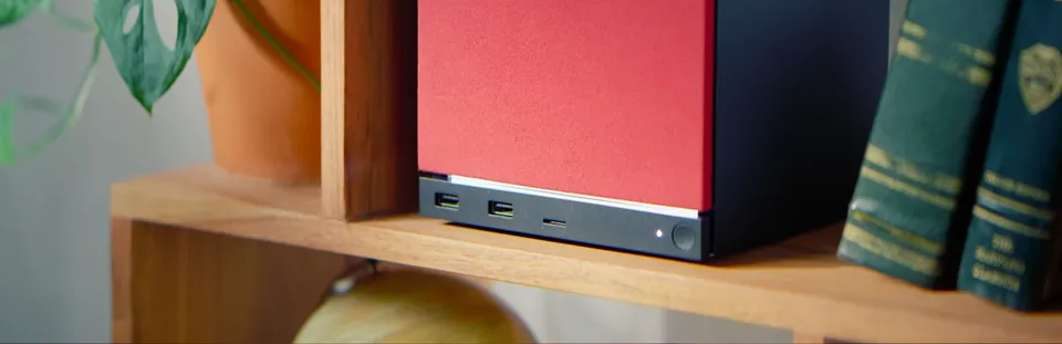 A Steam Machine with a red fabric faceplate on a bookshelf