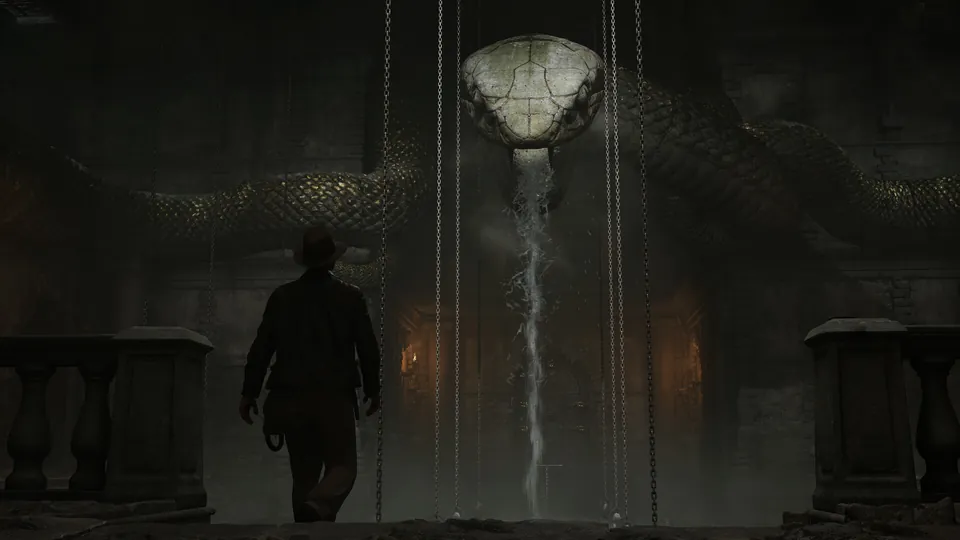 Indy walks toward a giant serpent statue and a glowing waterfall in an underground chamber