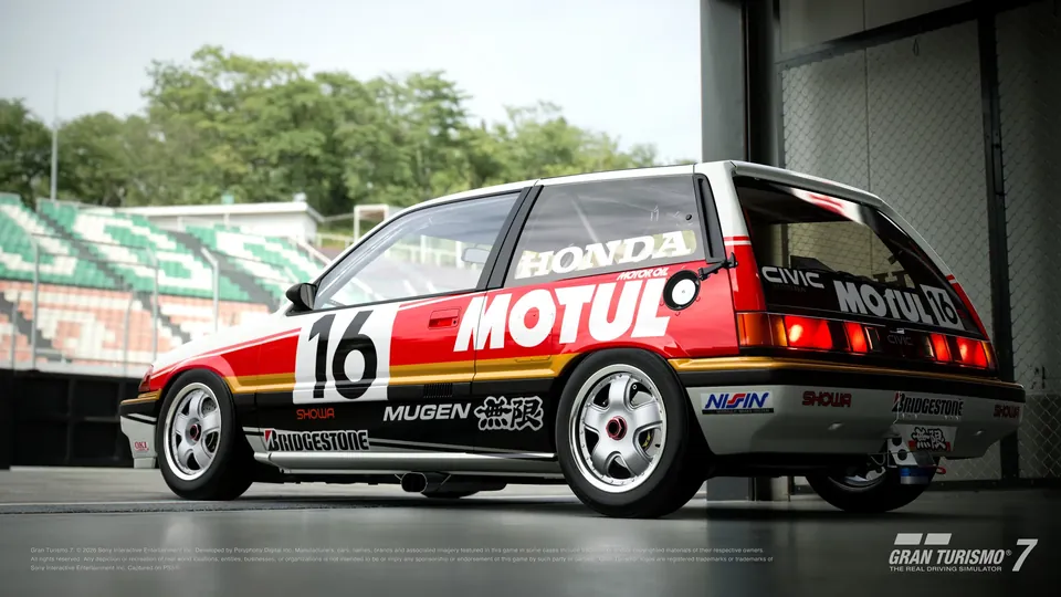 The Honda Civic Si Group A in red, white and yellow Motul livery with the number 16, parked in a pit garage