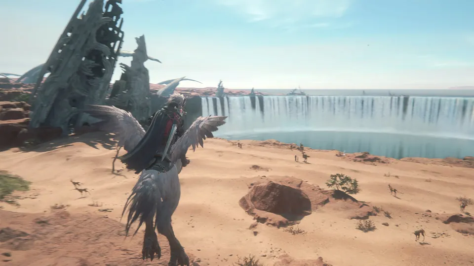 A rider on a feathered bird crosses a desert toward a huge waterfall and a ruined tower in Final Fantasy XVI