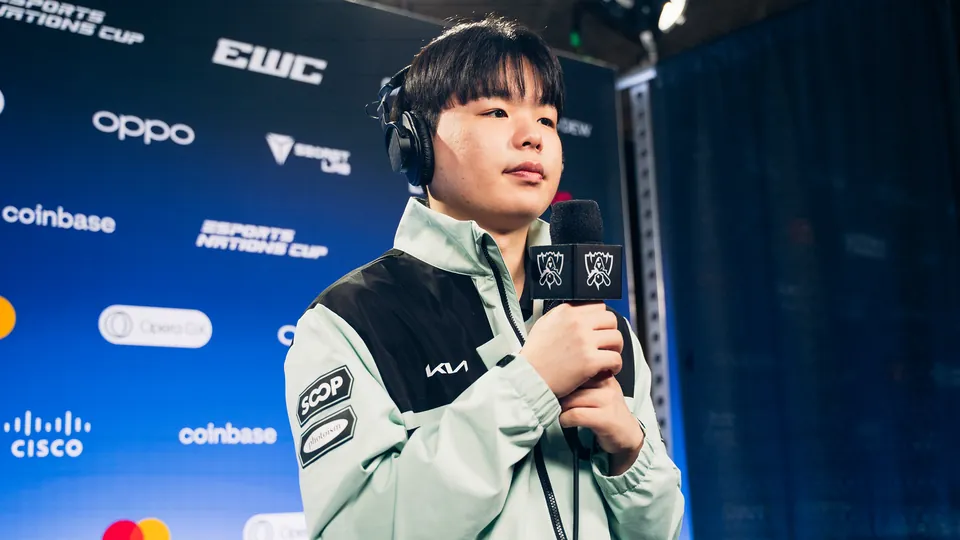 A Dplus KIA player in a mint team jacket holds a Worlds microphone at the Worlds 2026 Swiss Stage media day