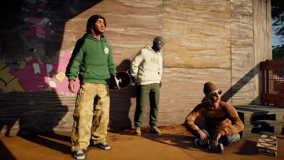 Three skaters hang out against a wooden wall covered in stickers, one sitting with a board, in skate.