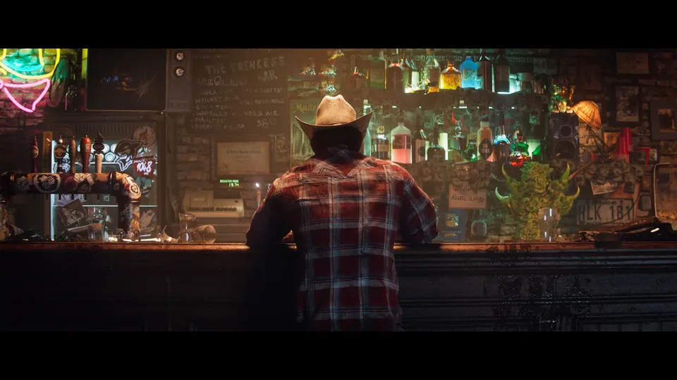 Marvel's Wolverine image: Logan in a cowboy hat sits at a neon-lit bar lined with bottles