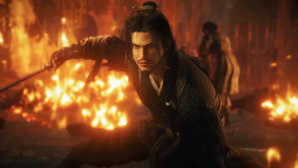 A warrior with a sword crouches among the flames of a burning camp in Wo Long 2