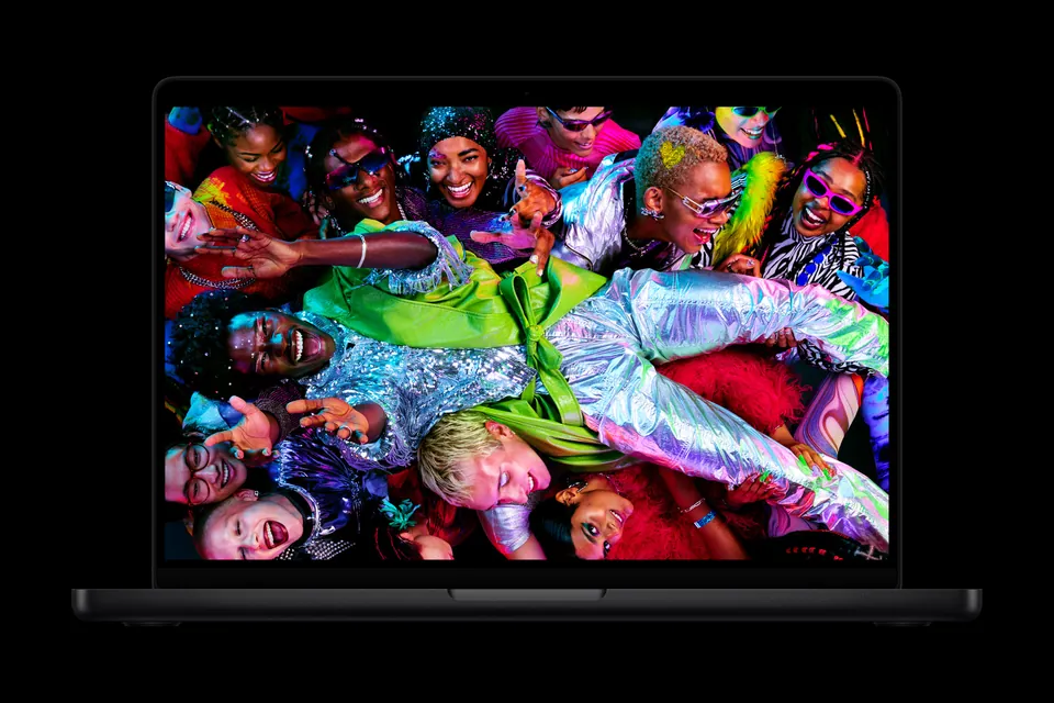 A space black 14-inch MacBook Pro with M5 showing a colorful crowd photo on its Liquid Retina XDR display