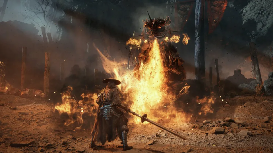 Soul stands with a spear in front of a giant burning figure as flames sweep across the ground in Phantom Blade Zero