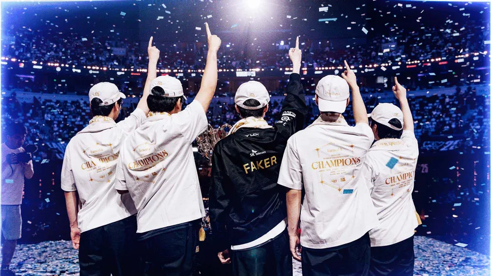 T1 players in white champions shirts and caps pointing up at confetti in a packed arena, Faker in a black jacket in the middle