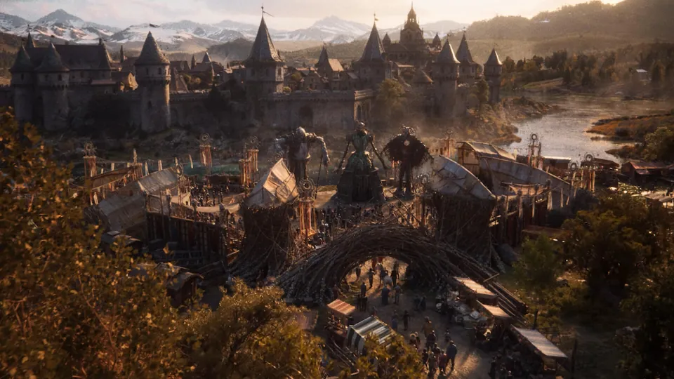 A walled medieval city with spires and a winding river under snowy mountains in the Divinity reveal trailer