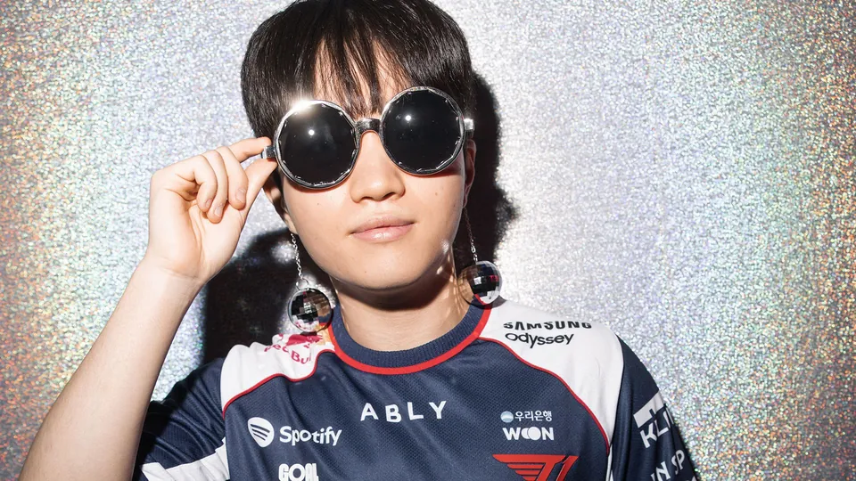 A T1 player in the navy T1 jersey with Spotify and ABLY logos, posing in round mirrored sunglasses