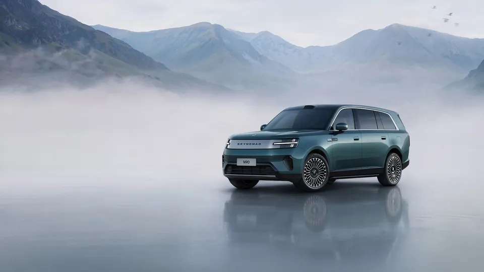 A green Xiaomi Pengcheng N90 Max SUV with Skynomad lettering on its nose, parked on a misty lake shore below mountains